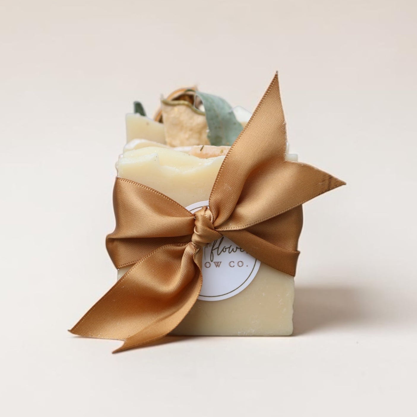 Bar of soap wrapped in a gold ribbon on a light beige background